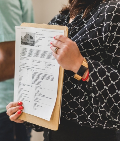 REALTOR Holding MLS Listing Printout in Her Hand